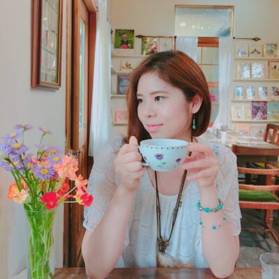 紅茶のカップを持った女と机の上に花瓶と花