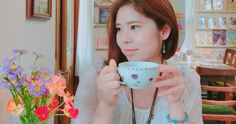 紅茶のカップを持った女と机の上に花瓶と花